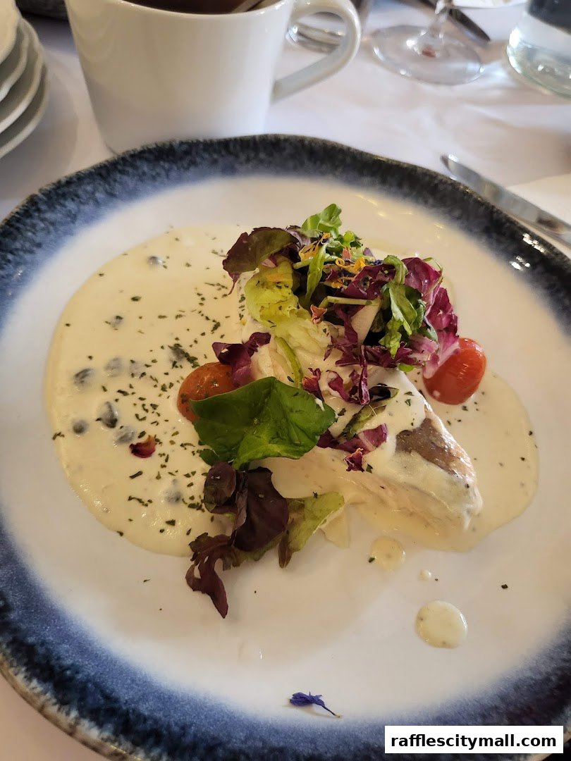 A beautifully plated dish with creamy sauce, fresh greens, and cherry tomatoes, served with a cup of coffee.