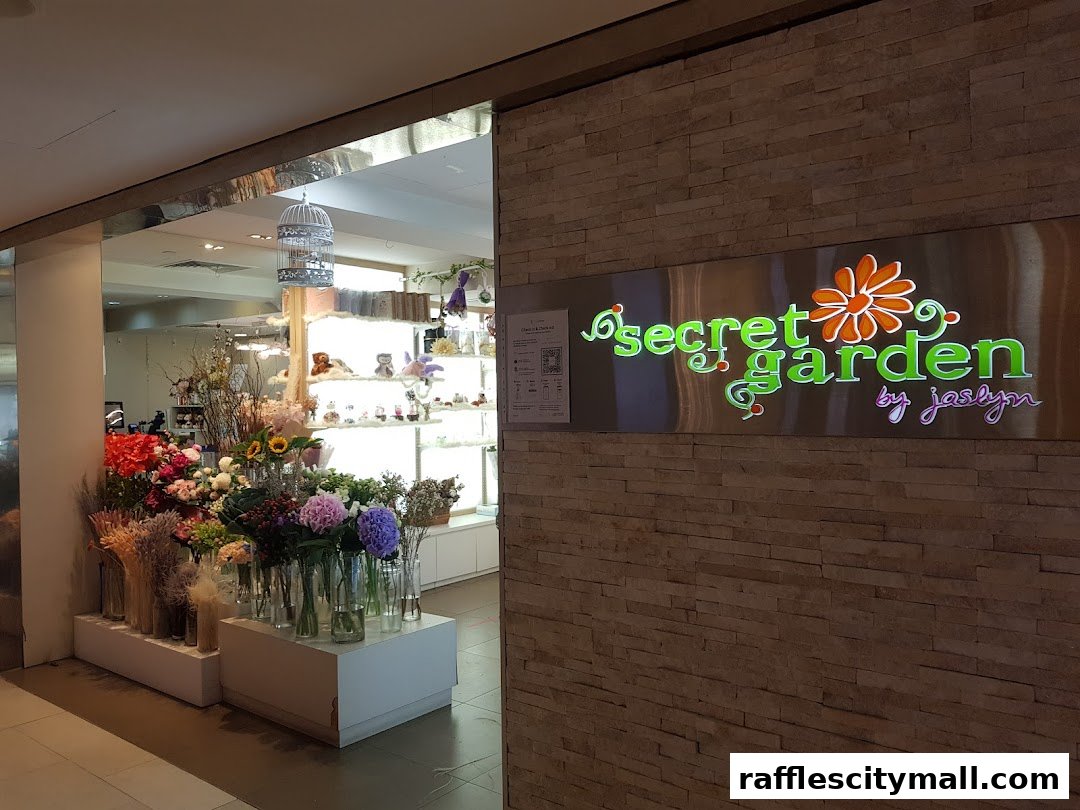 The entrance to Secret Garden flower shop, showcasing a vibrant display of fresh flowers and the shop's illuminated sign.