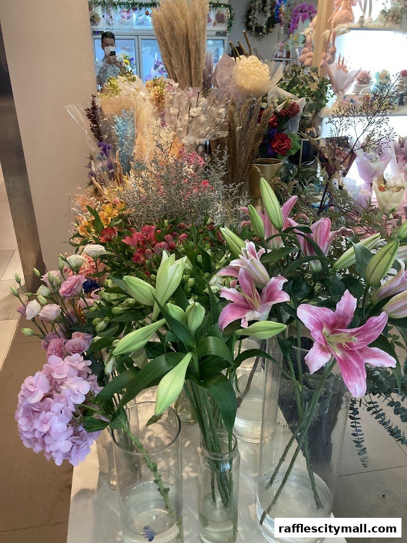 A vibrant display of fresh lilies and assorted dried flowers in clear vases.