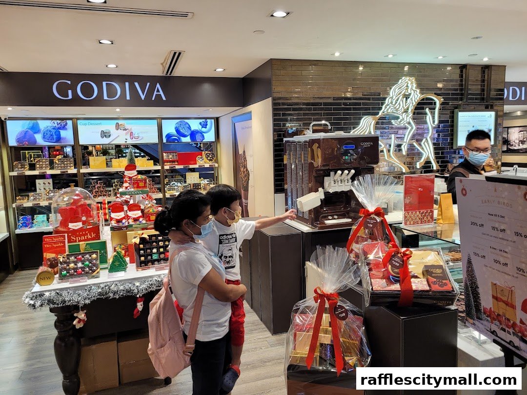 A mother and child look at Godiva chocolates and gift baskets, with a staff member behind the counter.