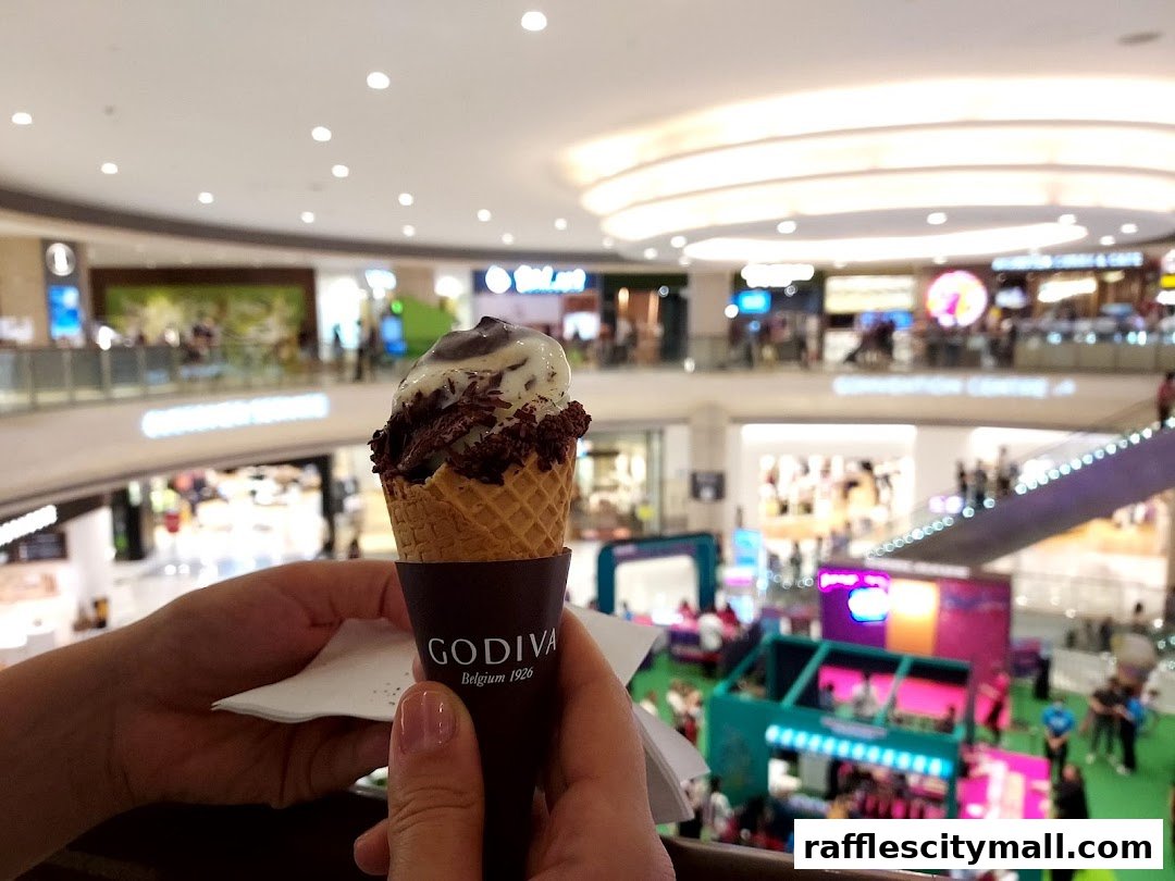 Hands holding a Godiva ice cream cone in a shopping mall.