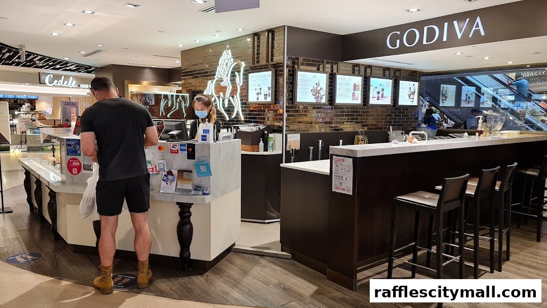 A Godiva chocolate shop with a counter, seating, and customers being served.