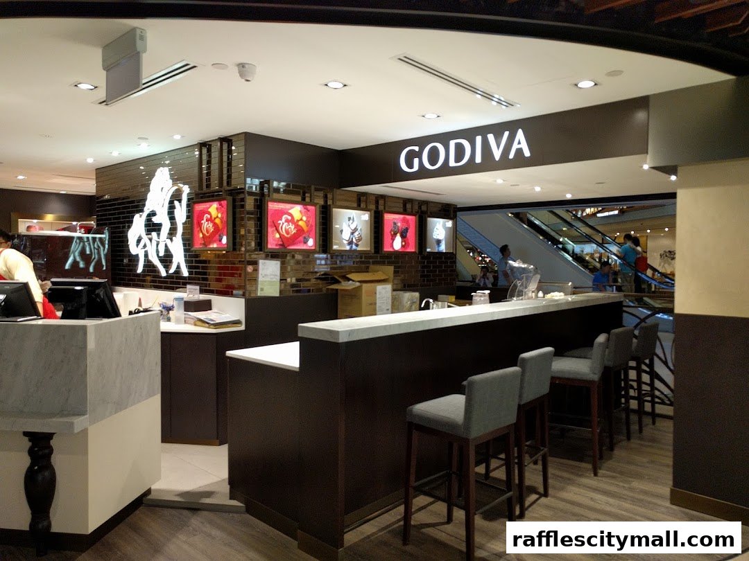 Interior view of a Godiva chocolate shop with a counter, seating, and displays.
