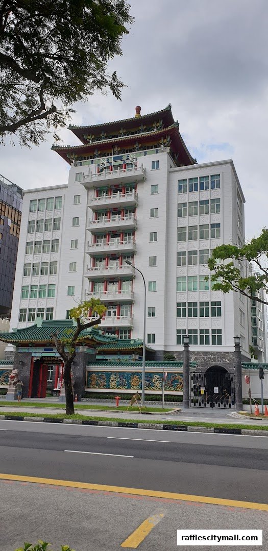 A large white building with traditional East Asian architectural elements and a street in front.