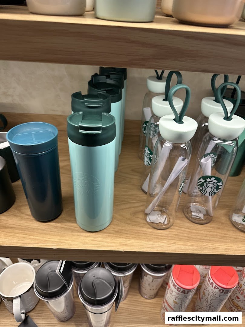 A display of Starbucks tumblers and water bottles on wooden shelves.