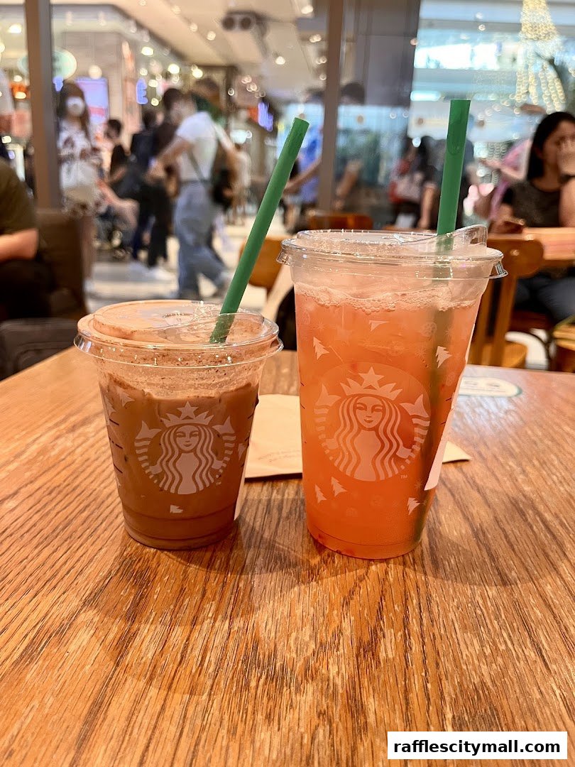 Two Starbucks drinks, one chocolate and one fruity, sit on a wooden table.