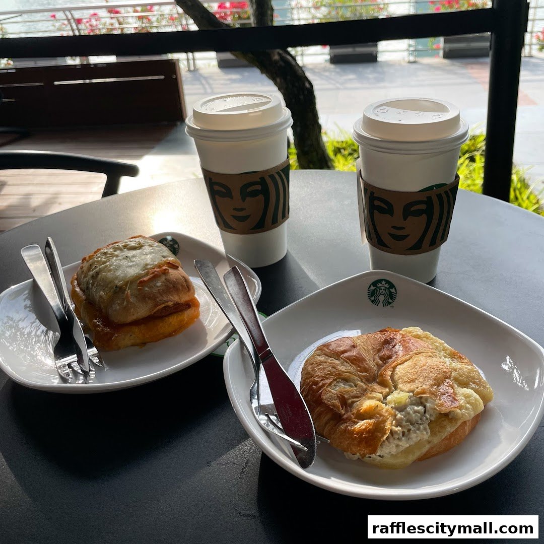 Two Starbucks coffees and two pastries on a table with cutlery.