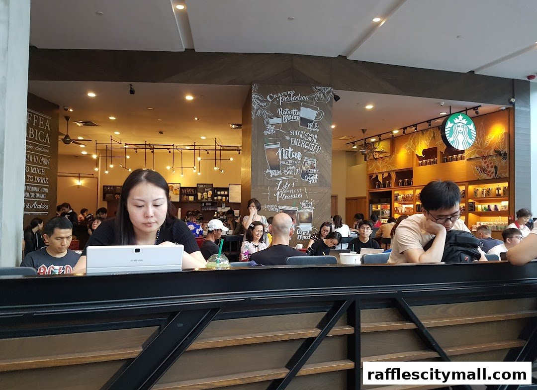 People are seated inside a busy Starbucks cafe, some working on laptops.