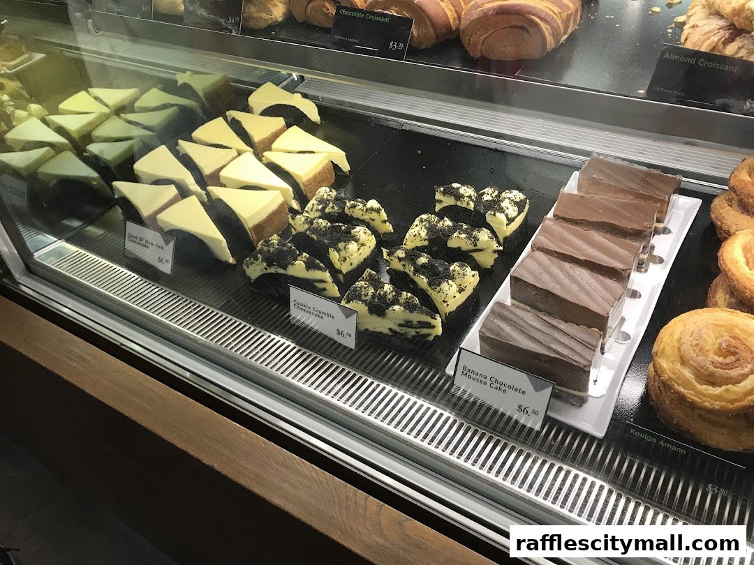 A display case filled with various cakes and pastries, including cheesecakes and croissants.