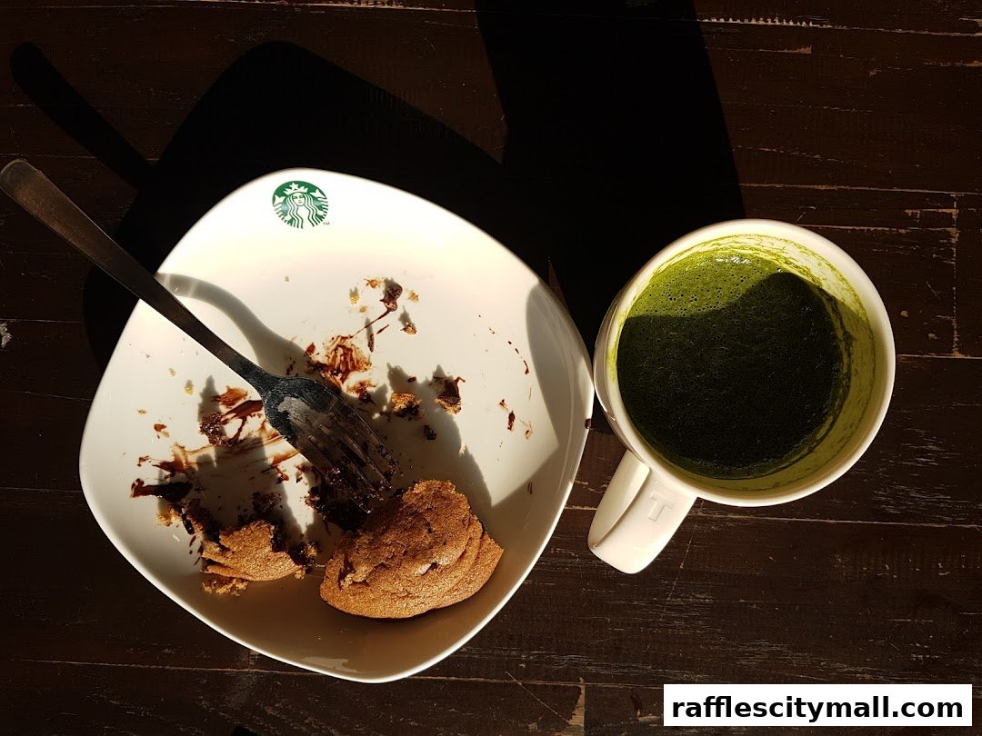 A partially eaten cookie and a matcha drink on a wooden table.
