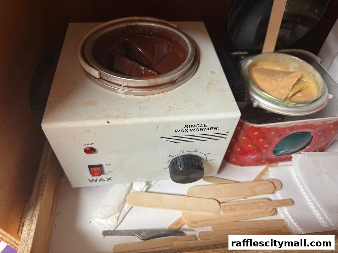 A close-up of a wax warmer with wax and applicators, suggesting a beauty treatment.