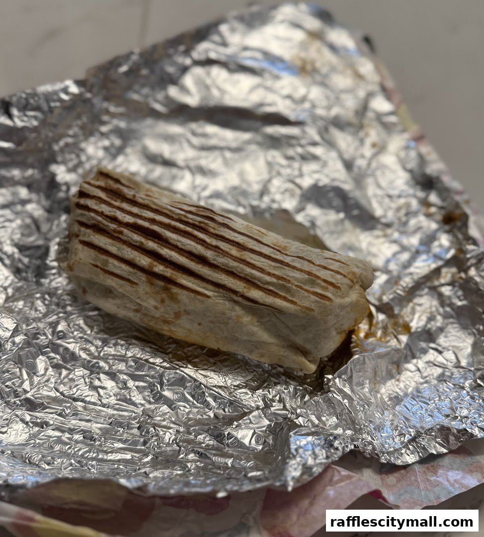 A close-up shot of a grilled burrito wrapped in foil.