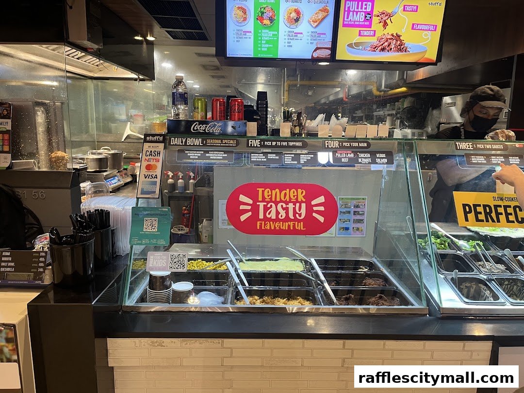 A food counter at Stuffd with various ingredients and a menu board above.