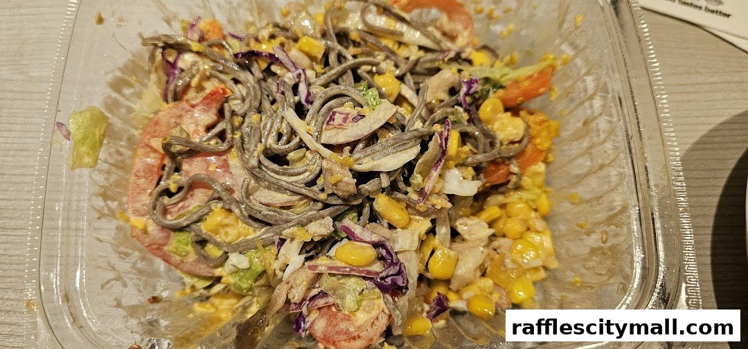 A close-up of a healthy soba noodle salad with corn, tomatoes, and shredded cabbage.