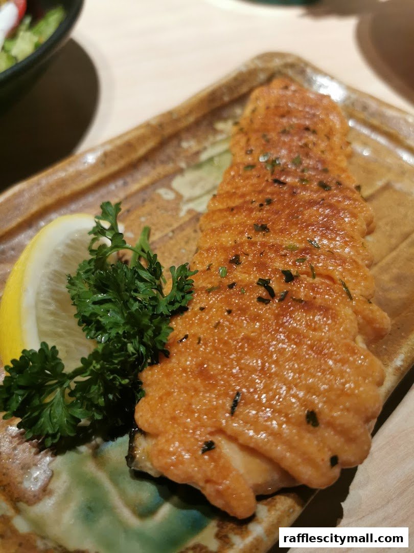 A close-up of a delicious salmon dish with a creamy topping, garnished with lemon and parsley.