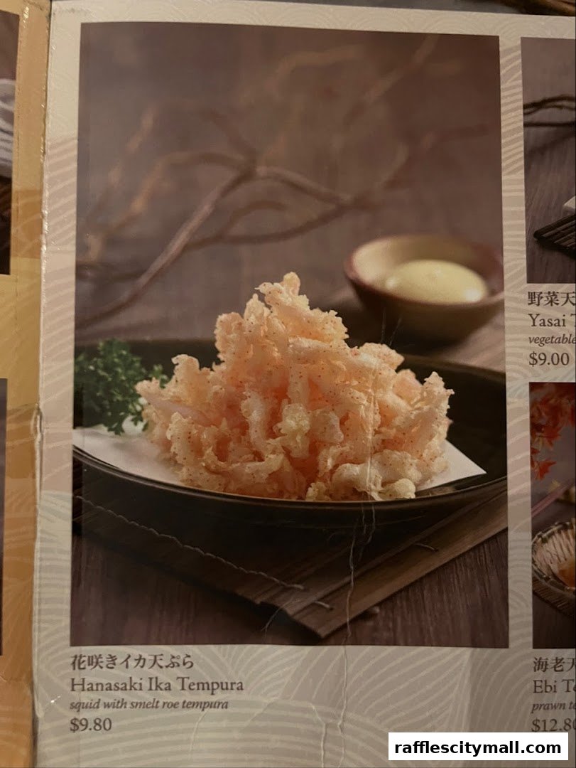 A close-up of a menu item featuring crispy tempura with a side of dipping sauce.
