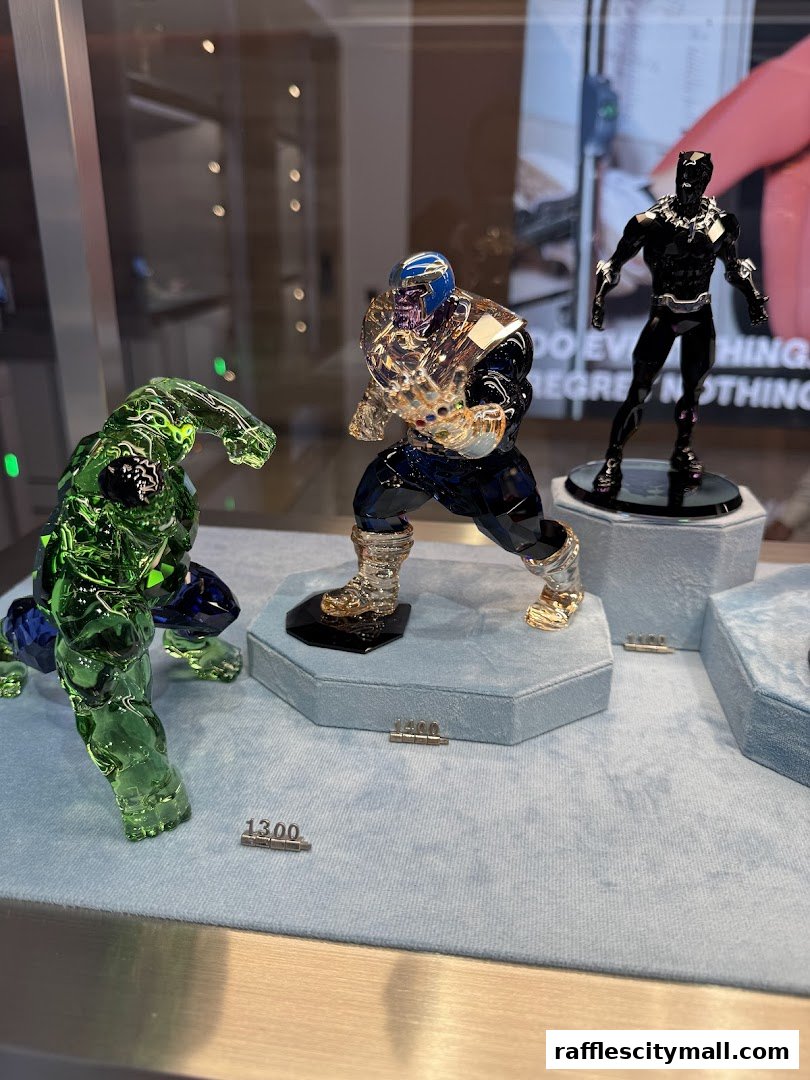 Swarovski crystal figurines of Marvel characters Hulk, Thanos, and Black Panther displayed in a shop window.