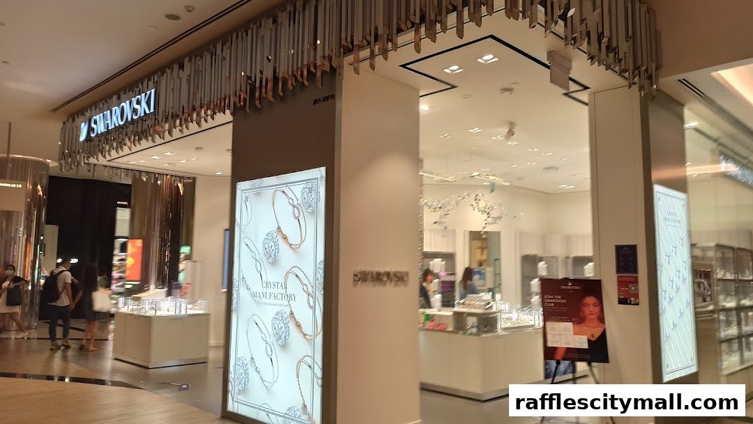 The entrance of a Swarovski store with illuminated displays of jewelry and a promotional poster.