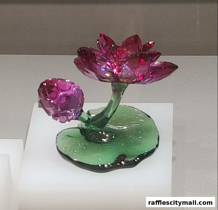 A sparkling crystal lotus flower figurine with a bud on a green leaf base.