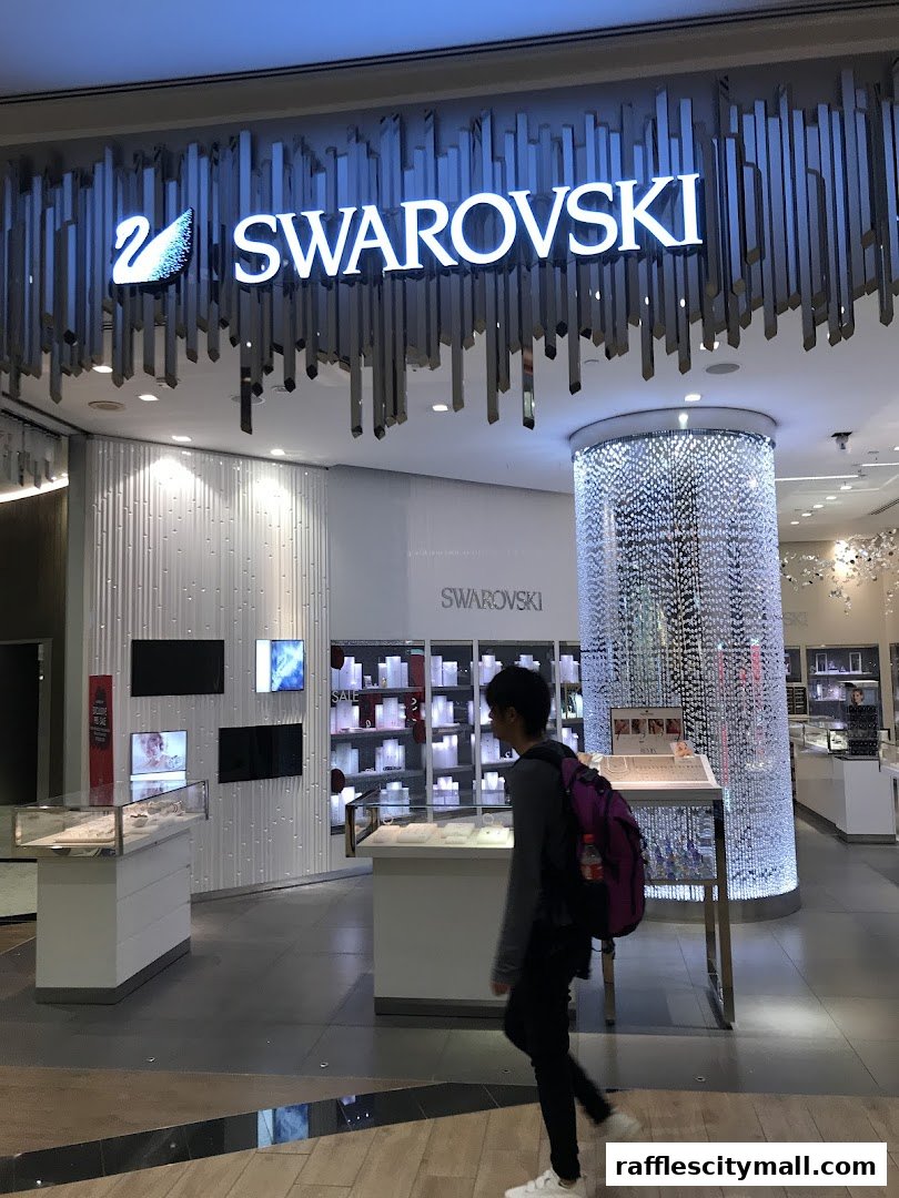 A person walks past the illuminated Swarovski store entrance with sparkling displays.