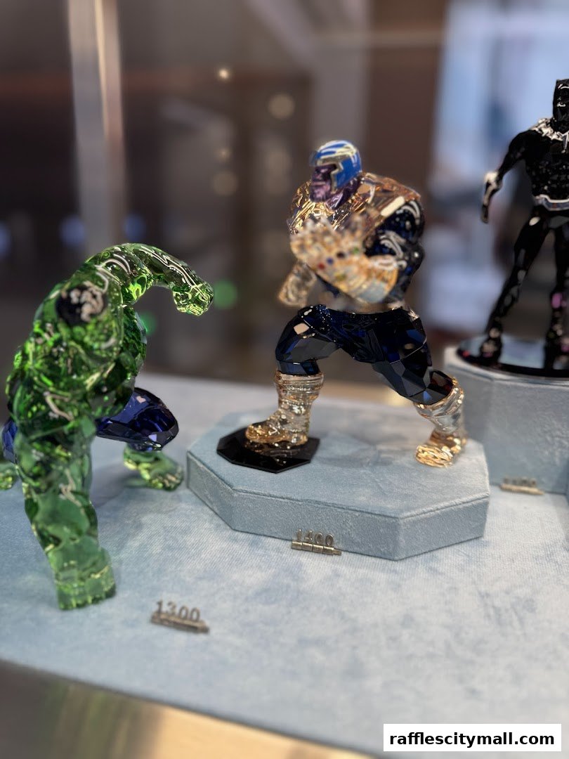 Swarovski crystal figurines of Marvel characters Hulk, Thanos, and Black Panther displayed in a shop window.