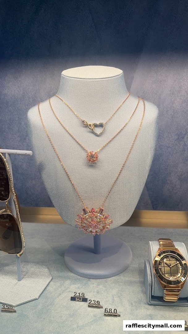 A display of necklaces and a watch in a retail store window.