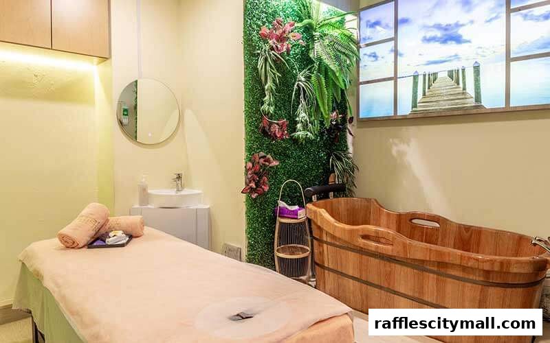A serene spa room with a massage bed, wooden tub, and a calming nature-themed wall.