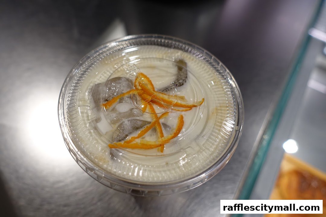 A close-up overhead view of a refreshing iced coffee drink with orange peel garnish.