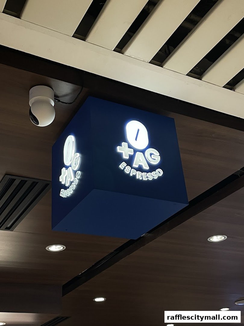 A cubic sign for TAG Espresso with illuminated lettering hangs from the ceiling.