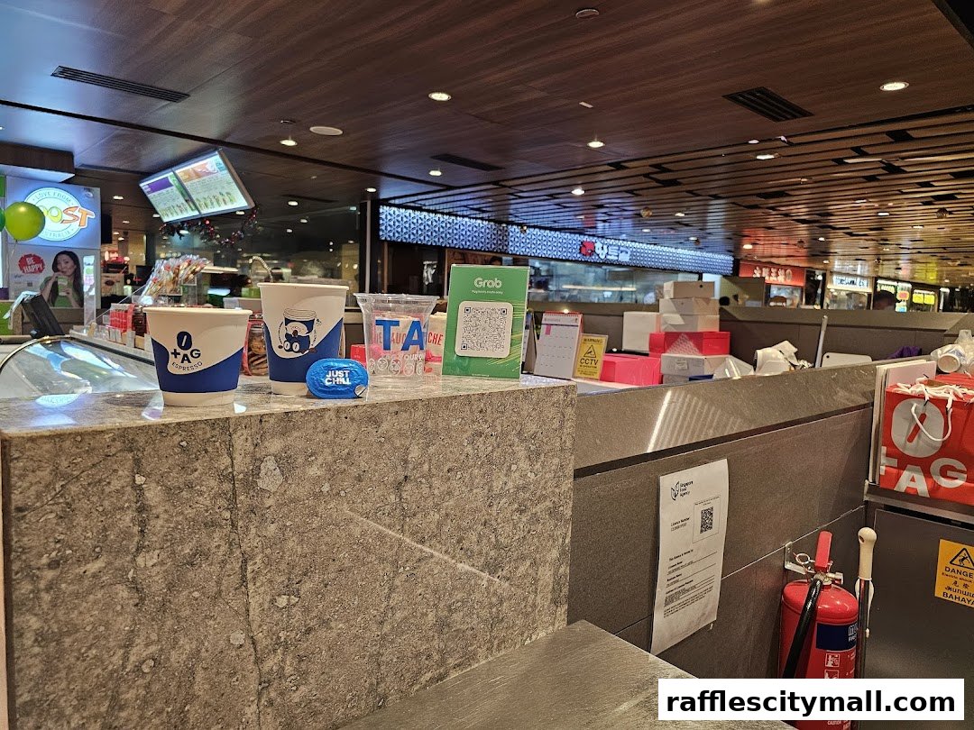 Counter at TAG Espresso with coffee cups, Grab QR code, and fire extinguisher.