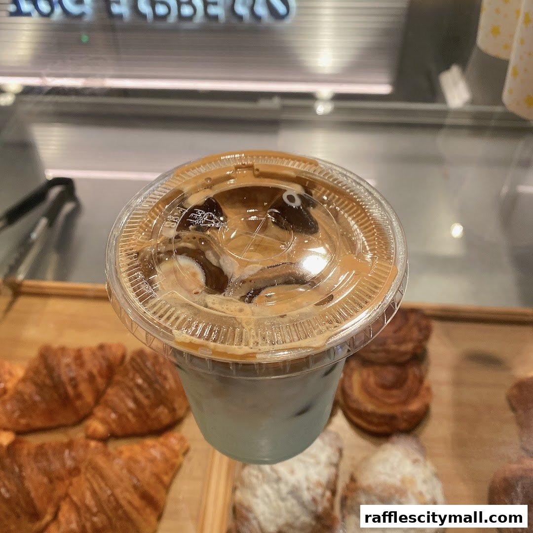 A close-up of an iced coffee with milk and caramel drizzle, next to pastries.
