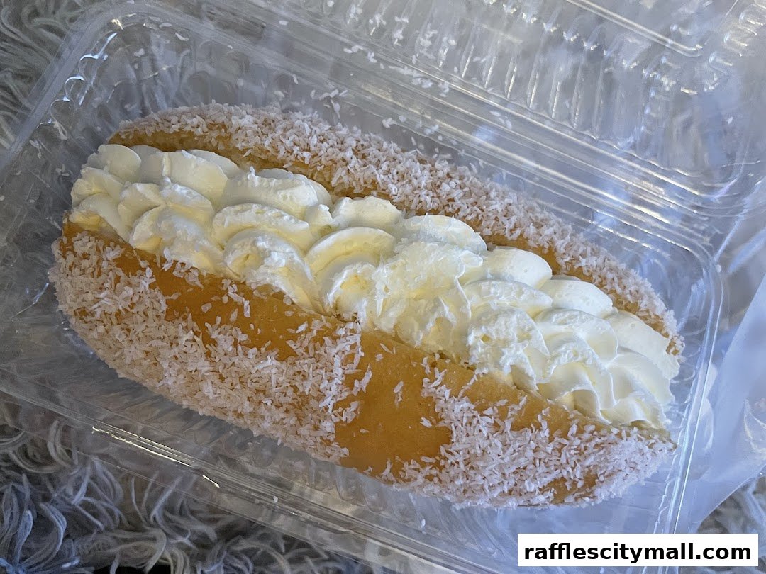 A close-up of a coconut-covered pastry filled with whipped cream.