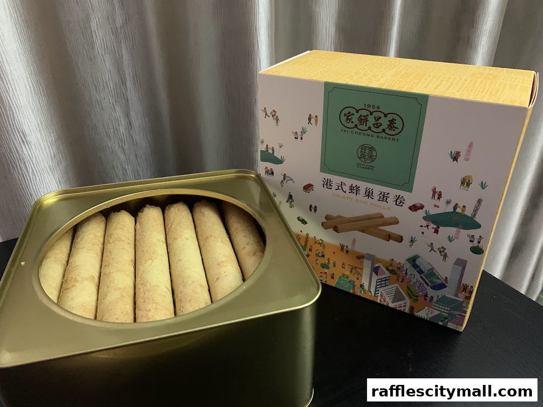 A tin of crispy egg rolls from Tai Cheong Bakery next to its decorative packaging.