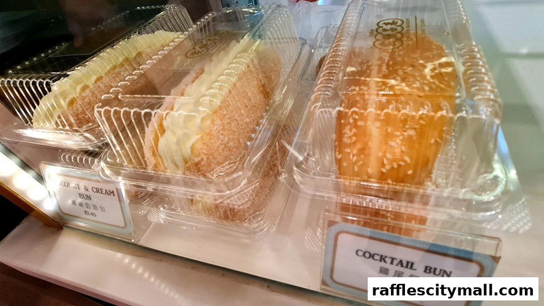 Close-up of freshly baked buns with cream and coconut, and cocktail buns in clear packaging.