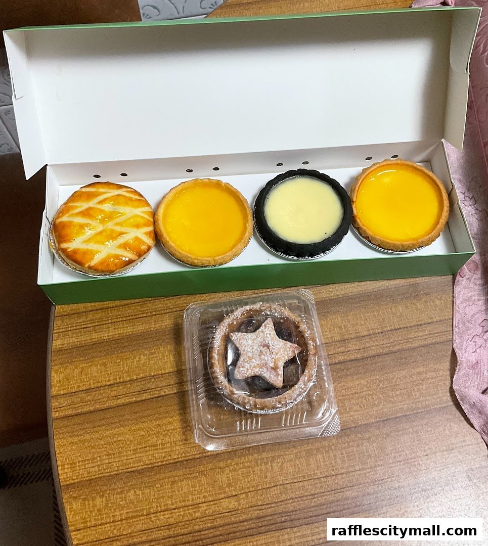 A box of assorted tarts and a single tart with a star on top, presented on a wooden surface.