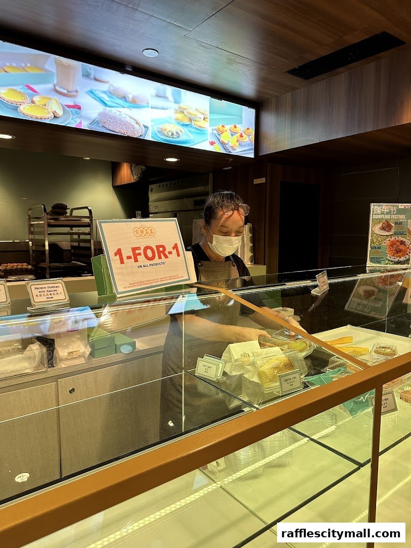 A bakery staff member serves customers behind a display case filled with pastries.