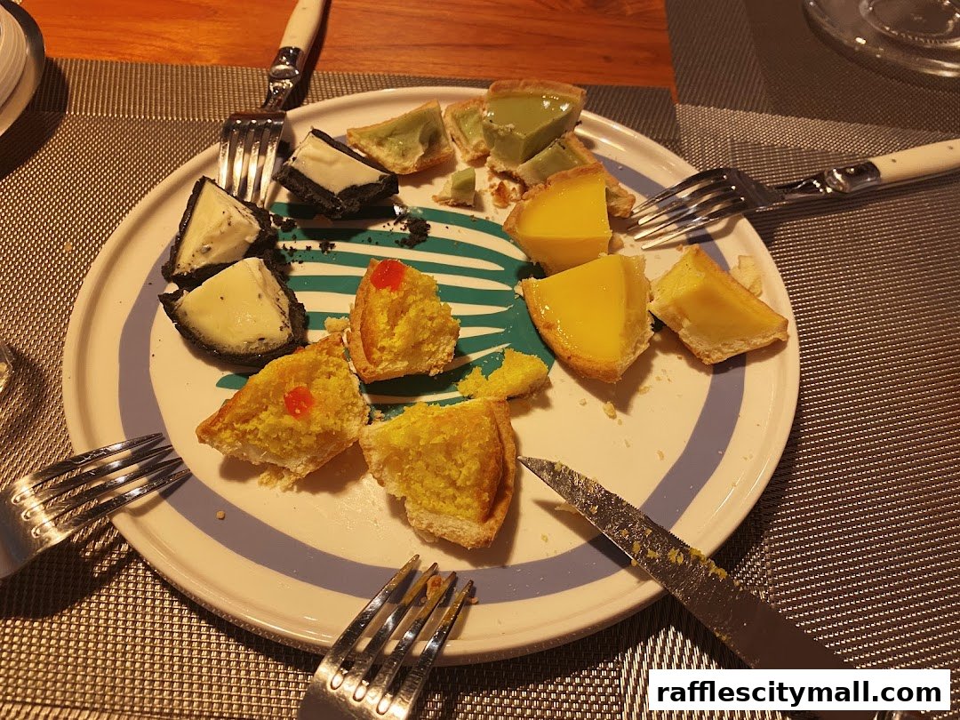A plate of assorted mini tarts and pastries, partially eaten, with forks and a knife.