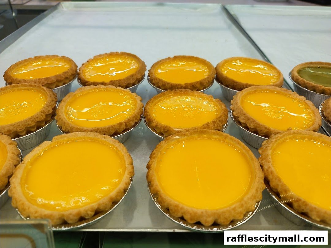 A close-up shot of freshly baked egg tarts with a glossy, golden custard filling.