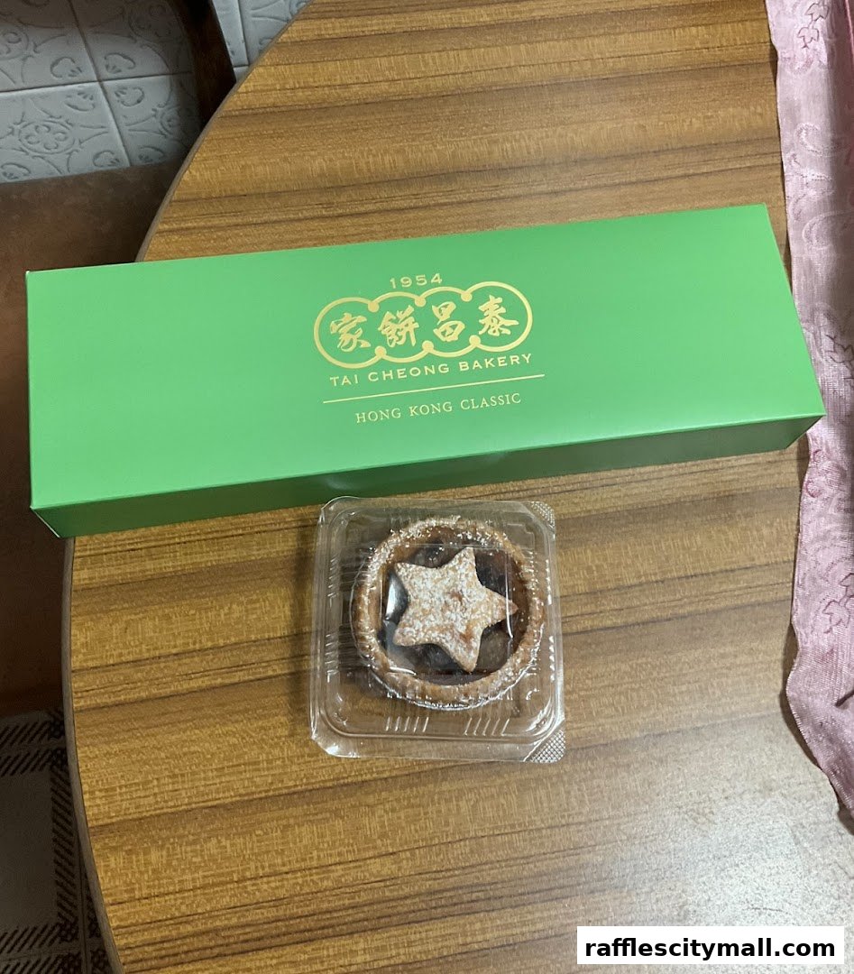 A green Tai Cheong Bakery box with a single pastry in a plastic container.