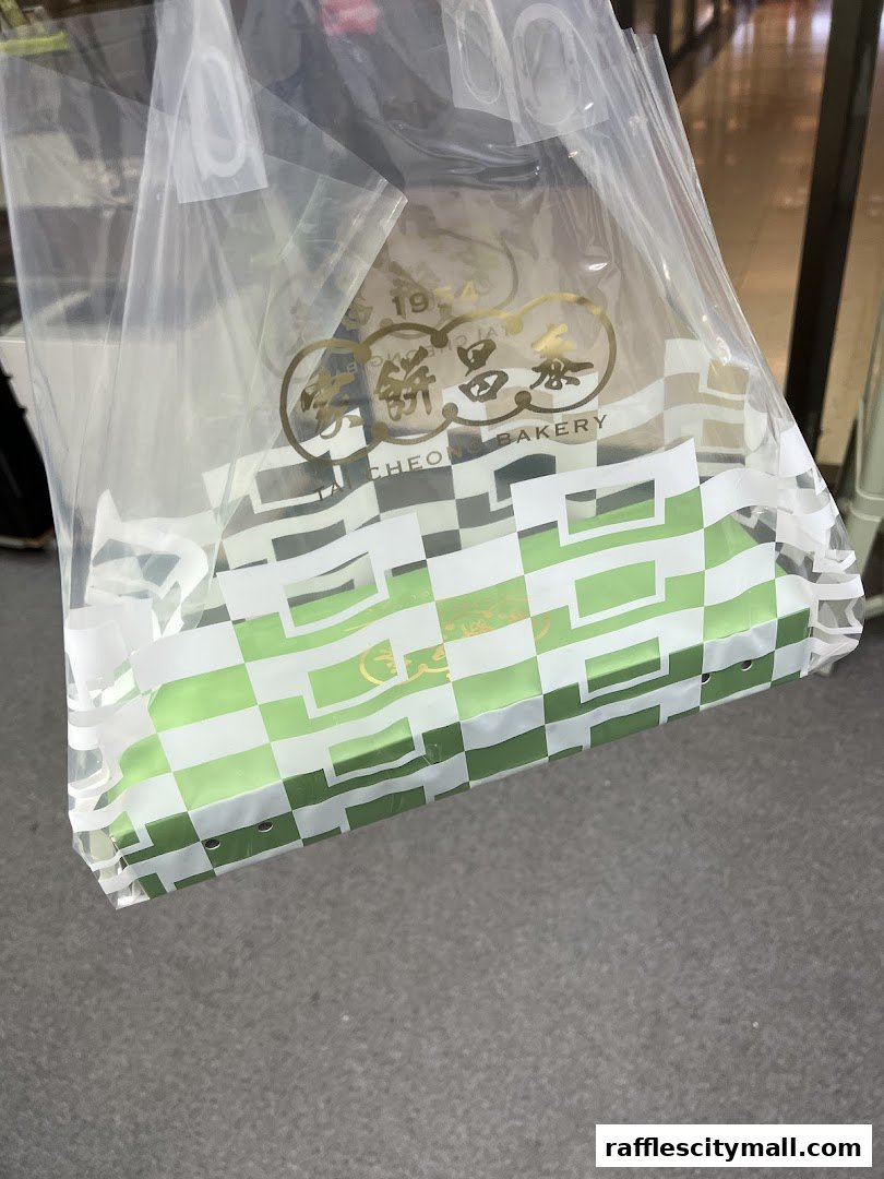 A clear plastic bag from Tai Cheong Bakery with a green checkered pattern and gold logo.
