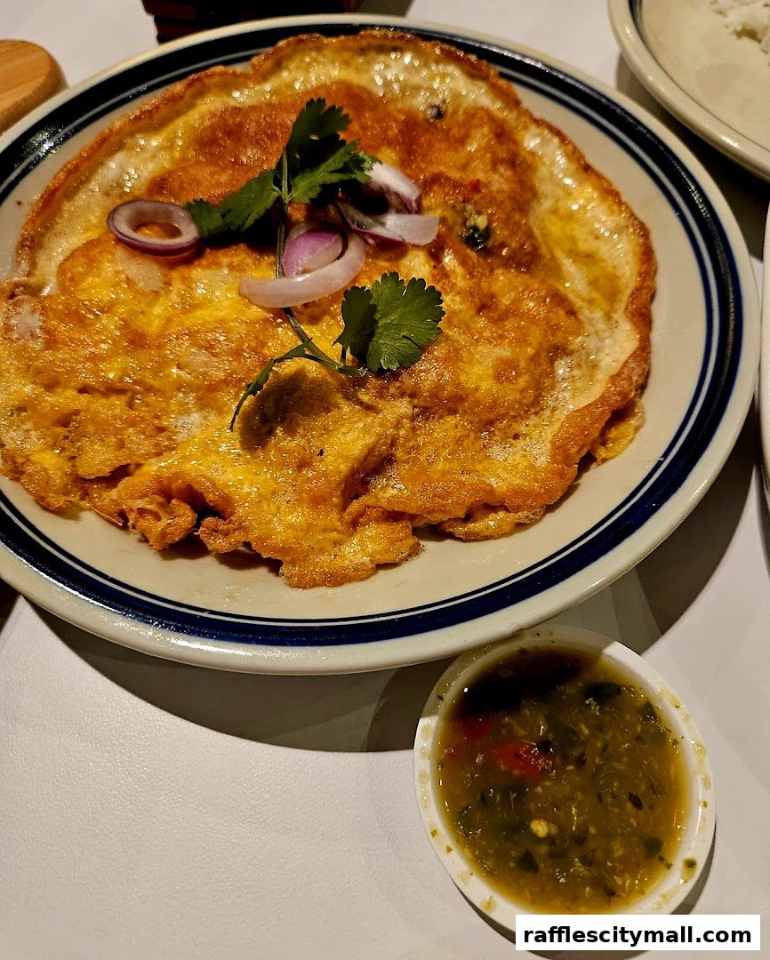 A close-up of a golden-brown omelet with red onion and cilantro, served with a side of green sauce.