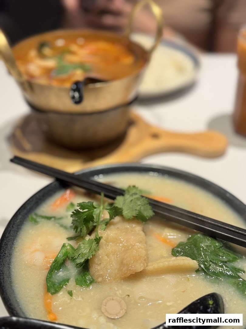 Close-up of two bowls of Thai food, one with soup and the other with noodles and vegetables.