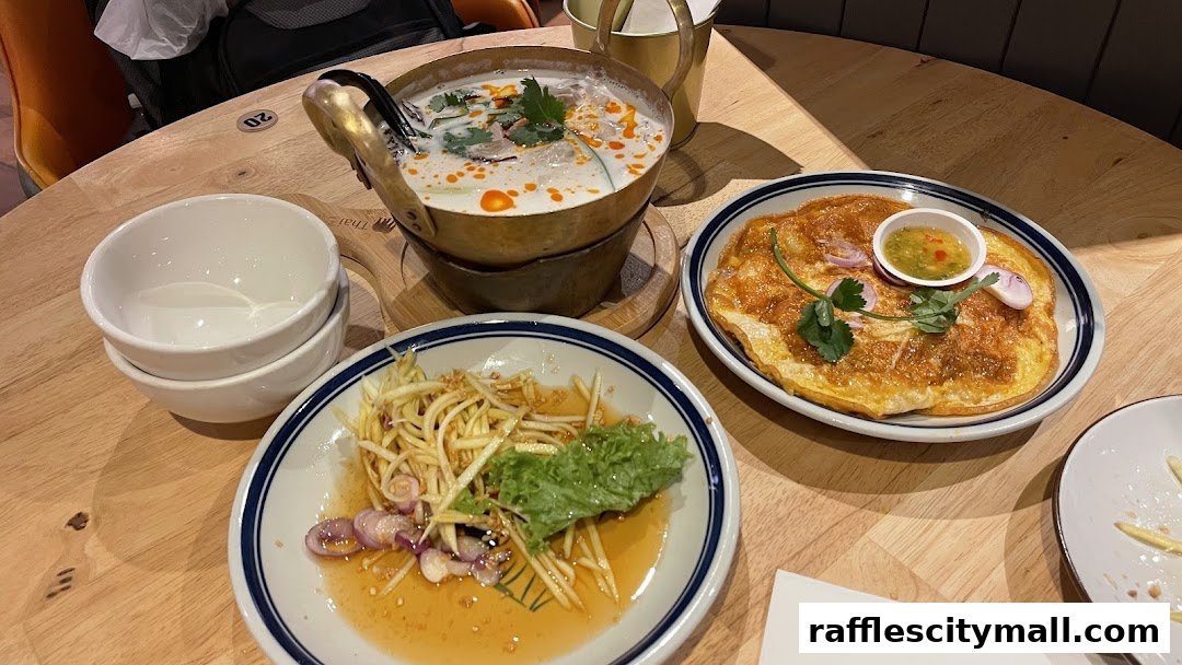 A table setting with Thai dishes including soup, omelet, and salad.