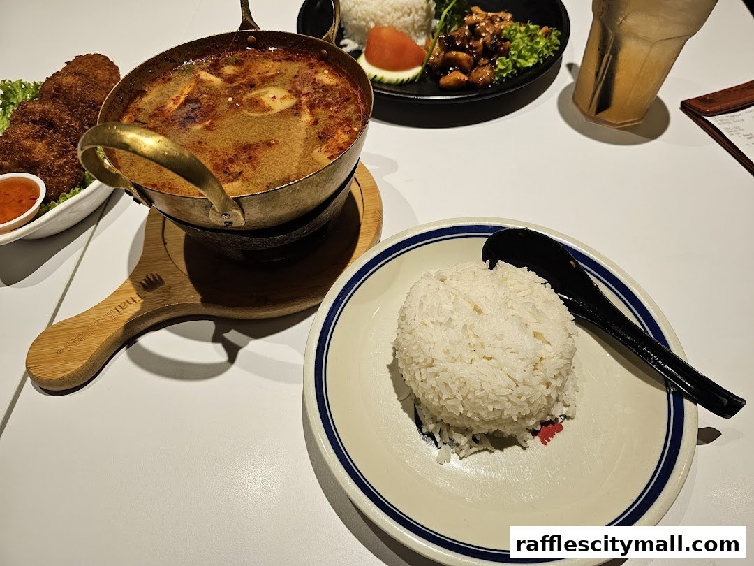 A table setting with Thai food, including Tom Yum soup, rice, and fried items.