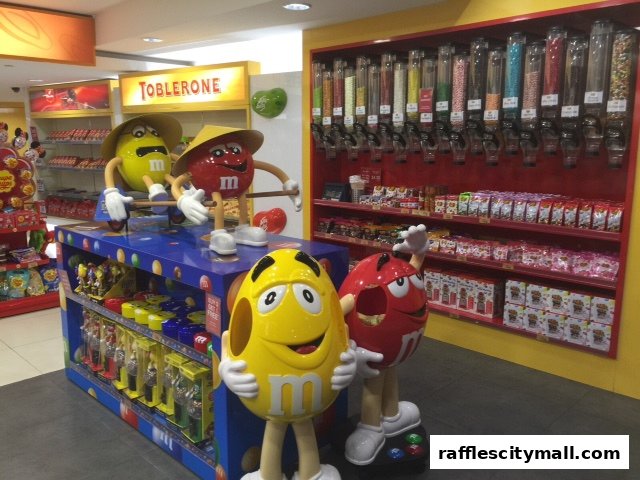 A vibrant candy store interior featuring M&M characters and a wall of candy dispensers.