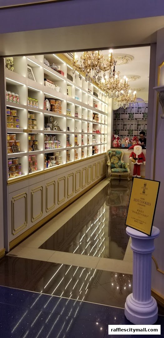 Interior of a beautifully decorated cookie shop with shelves stocked with cookies and elegant chandeliers.