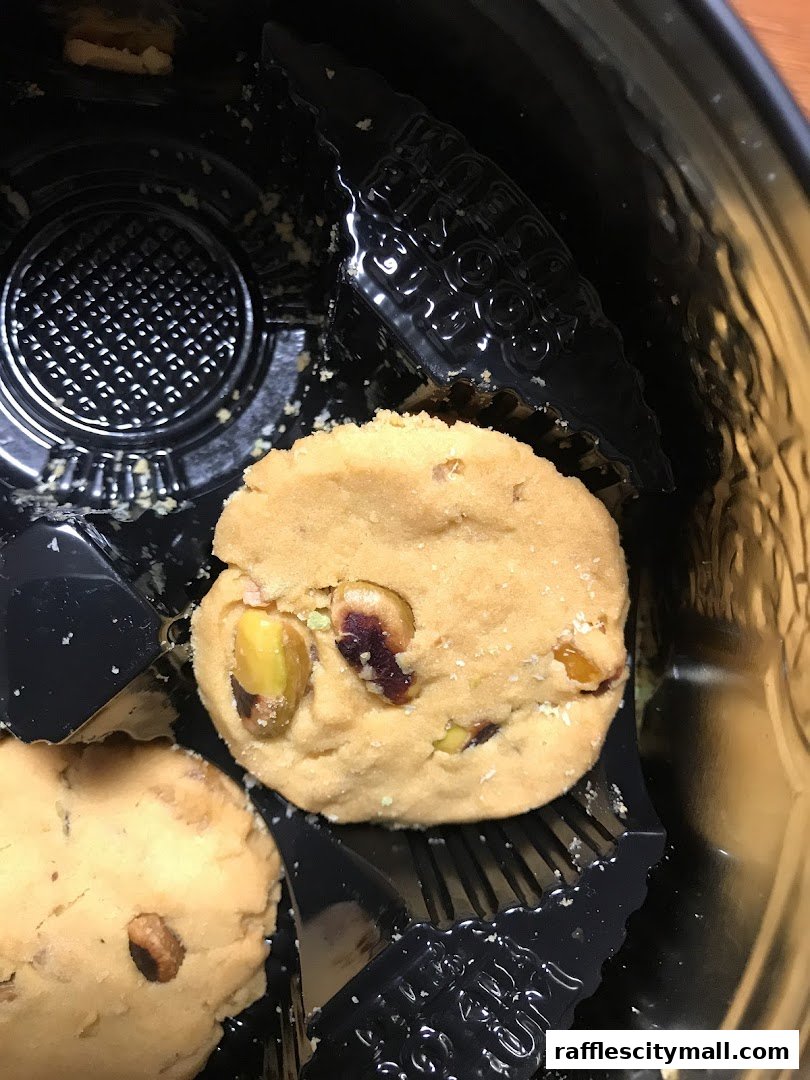 A close-up of two delicious cookies with pistachios and dried fruit in a black container.
