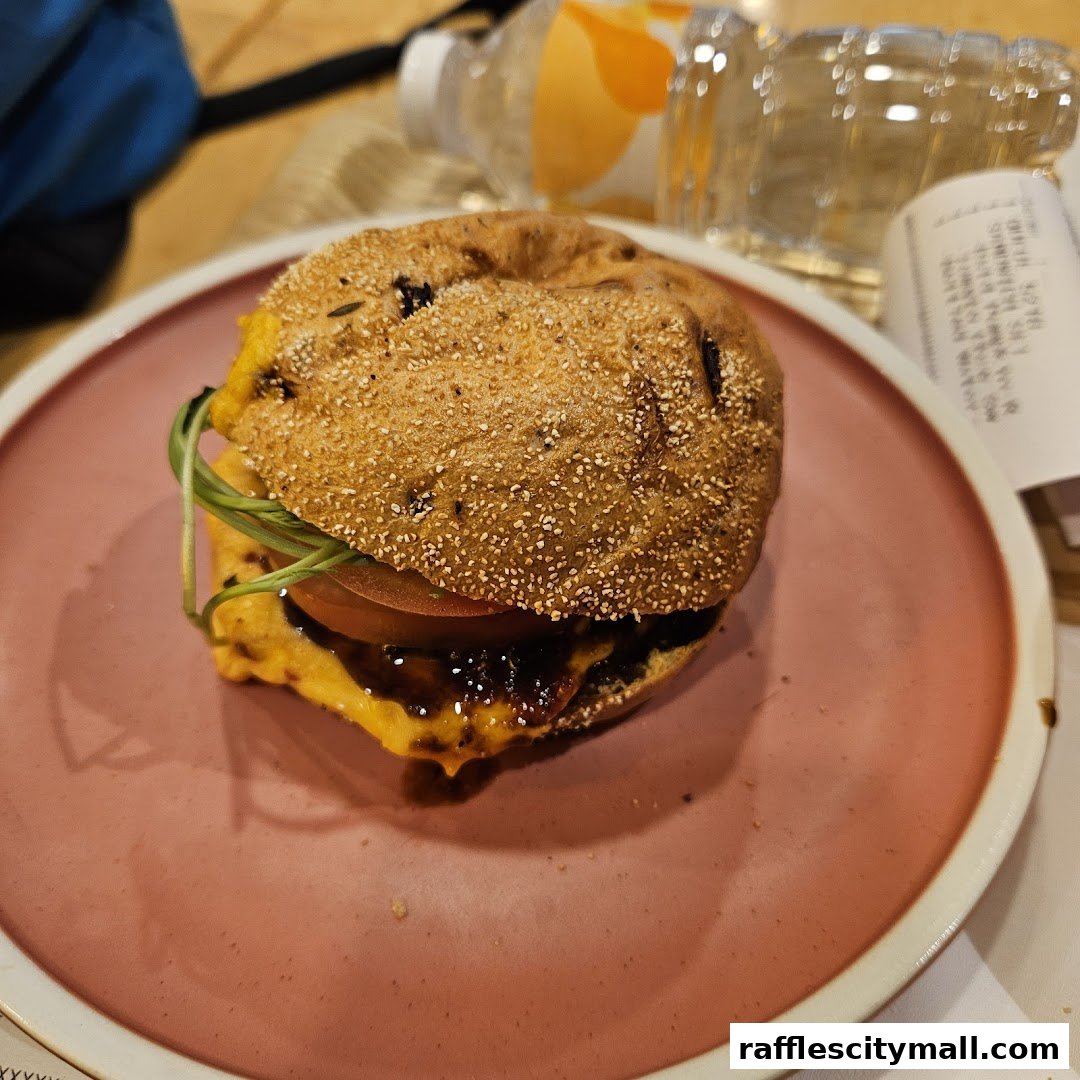 A close-up shot of a gourmet burger on a pink plate with a bottle of water in the background.