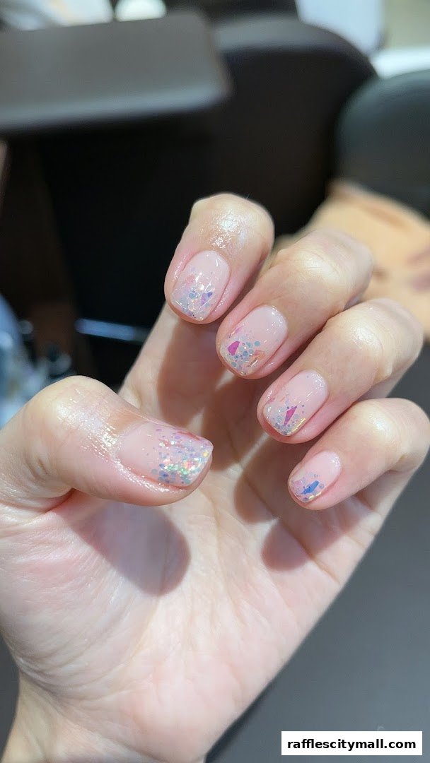 Close-up of a hand with a natural-looking manicure featuring glitter accents.