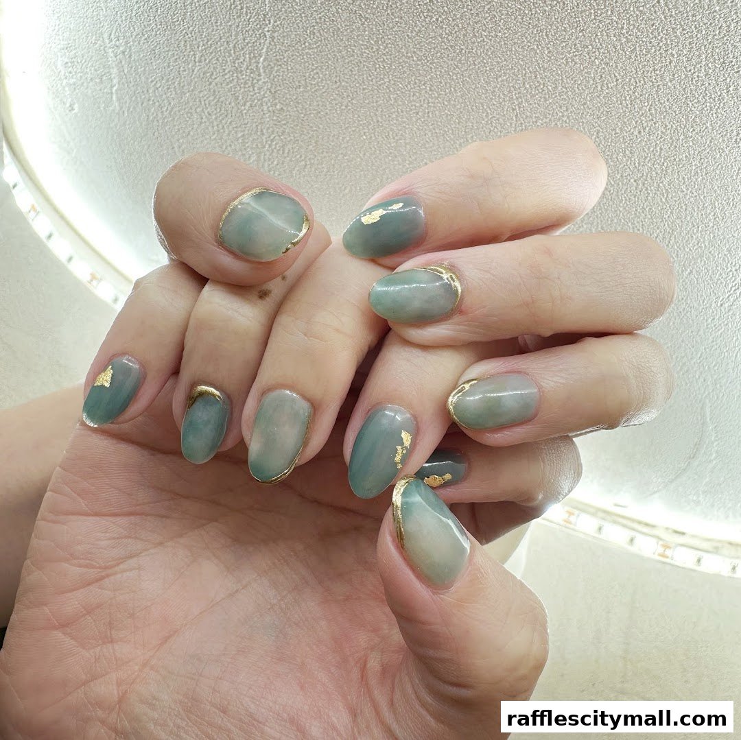 Close-up of hands with elegant green and gold nail art.
